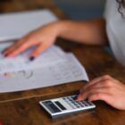 Pessoa faz cálculos na calculadora e consulta planilha