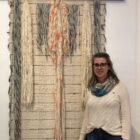 Mulher loira de óculos na frente de painel de tecido