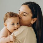 Mulher abraça e beija bebê em seu colo