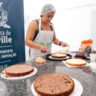 Mulher com touca na cabeça e avental prepara bolos