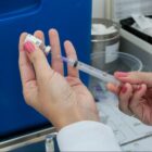 Mão de mulher segura seringa com vacina sendo preparada para ser aplicada