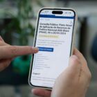 Pessoa segura celular nas mãos e na tela está a página para participar das consultas