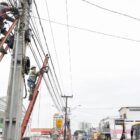 Técnicos em escadas trabalhando na fiação dos postes