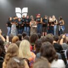 Coral se apresenta em palco para plateia sentada
