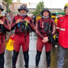Três homens com roupa de mergulho da Defesa Civil e um com roupa do Bombeiro
