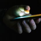 Pessoa segura celular em ambiente escuro