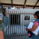 Agente de saúde na frente de uma casa ao lado de um militar