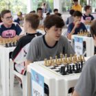Meninos disputam partidas de xadrez em duplas em mesas e cadeiras separadas