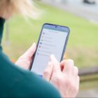Mulher segura celular e acessa o Joinville Fácil