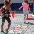 Duas meninas brincam em área aberta de escola