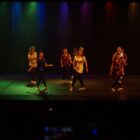 Mulheres se apresentam dançando no palco