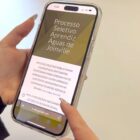 Mão feminina segura celular onde está aberta a página do Programa Jovem Aprendiz