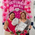 Duas mulheres seguram bambolê enfeitado com flores dentro de unidade de saúde
