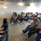 Homem em palco fala para plateia sentada