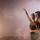 Casal dança coreografia em palco com efeito de fumaça