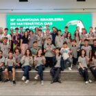 Alunos uniformizados seguram medalhas penduradas no pescoço e posam para foto