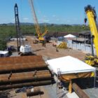 Guindastes, materiais para obra como peças metálicas, barraca em canteiro de obra onde começa a ser construída nova ponte