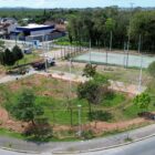 Imagem do alto de uma praça com área verde e quadra de esportes