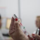 Mão de uma mulher segura frasco e uma seringa