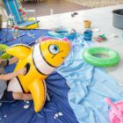 Três crianças brincam com boias em área de centro de educação infantil