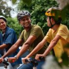 Quatro pessoas, três mulheres e um homem com capacetes, enfileirados em cima de bicicletas
