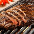 Pedaço de carne fatiada e assada em cima de grelha