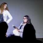 Duas mulheres encenam peça de teatro em palco