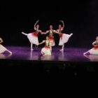 Oito bailarinas dançam coreografia clássica em palco, elas usam figurino