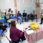 Mulheres e um homem em sala de aula sentados em cadeiras em um círculo conversam