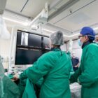 Equipe médica com uniforme verde em sala em hospital em procedimento, olha para telas