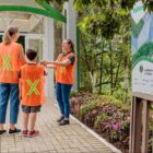 Duas mulheres e um menino, todos com colete laranja, entram em área do parque