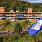 Fotografia da fachada da sede da Prefeitura de Joinville, com a bandeira da cidade na frente