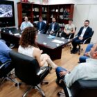 Homens e mulheres sentados em cadeiras em volta de uma mesa no gabinete do prefeito