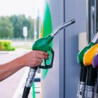 Mão de frentista segura bico de abastecimento em bomba de gasolina em posto
