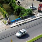 Carro trafega em rua asfaltada perto de um rio