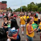 Foliões com camisetas de grupos em avenida durante Carnaval