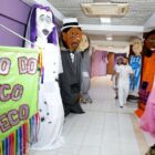 Casal anda por corredor com vários bonecos gigantes de Carnaval