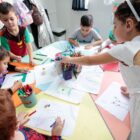 Crianças com fantasias desenham com lápis de cor em sala de aula