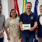 Prefeito, secretário, reitor e representante de universidade posam para foto, prefeito segura convite