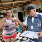 Homem com colete e boné entrega folheto para mulher