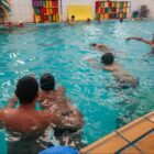 Meninos com touca nadam em piscina