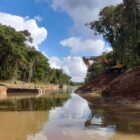 Escavadeira perto de um rio onde obras são realizadas