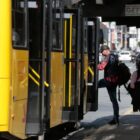 Ônibus parado em terminal, um homem embarca e uma mulher transita