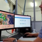 Homem olha para mapas em tela de computador