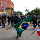 Agentes da Guarda Municipal uniformizados desfilam em avenida com bandeiras