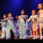 Crianças fantasiadas apresentam peça de teatro em palco