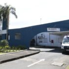 Fachada de Pronto Atendimento, uma construção azul, na frente há ambulâncias