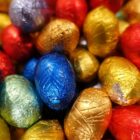 Vários ovos pequenos de chocolate embrulhados em papel brilhante de diferentes cores