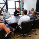 Homens e mulheres sentados em volta de uma mesa no gabinete do prefeito