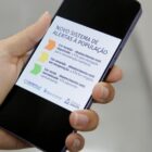 Pessoa segura celular na mão com informações sobre alertas